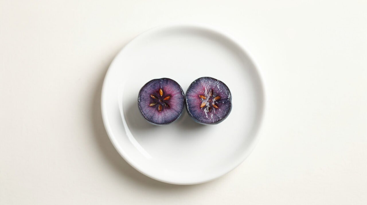 a single blueberry cut in half next to a small hamster food dish